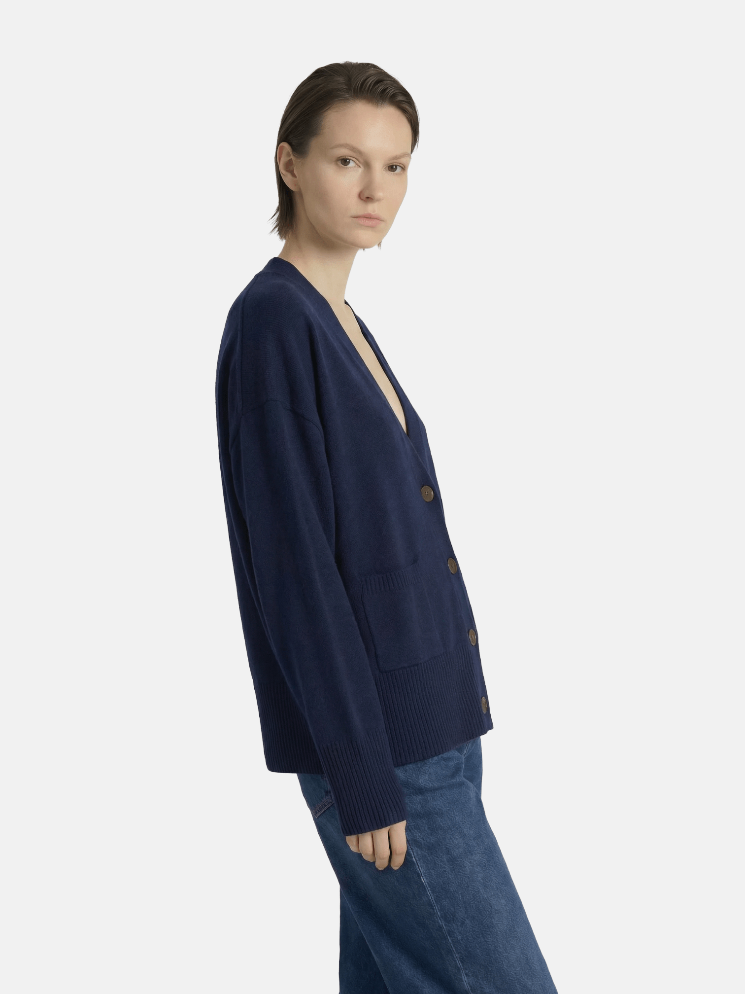 Person wearing a navy cardigan and jeans on a white background