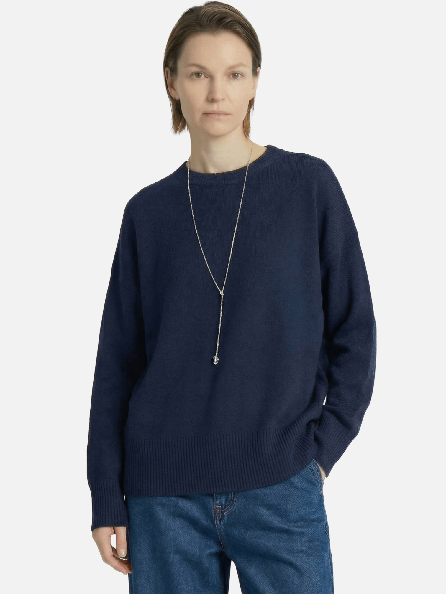 Person wearing a navy sweater and blue jeans on a white background