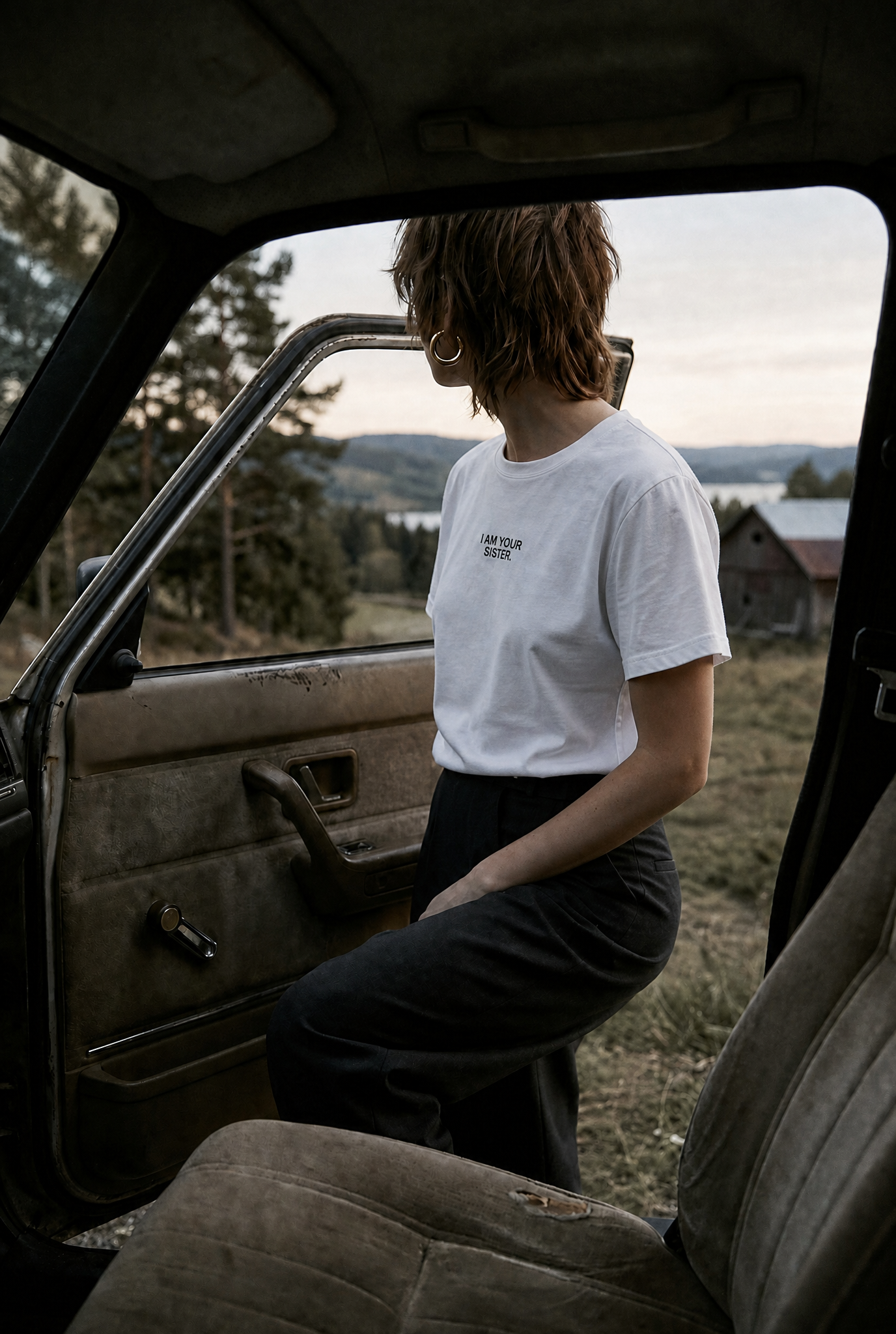 Person standing by an open car door in a scenic outdoor setting