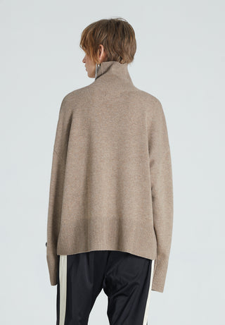 Back of woman wearing brown cashmere turtleneck. She is also wearing black trousers. 