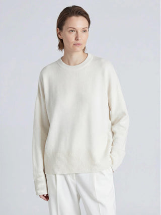 Person wearing a white sweater and pants on a light gray background